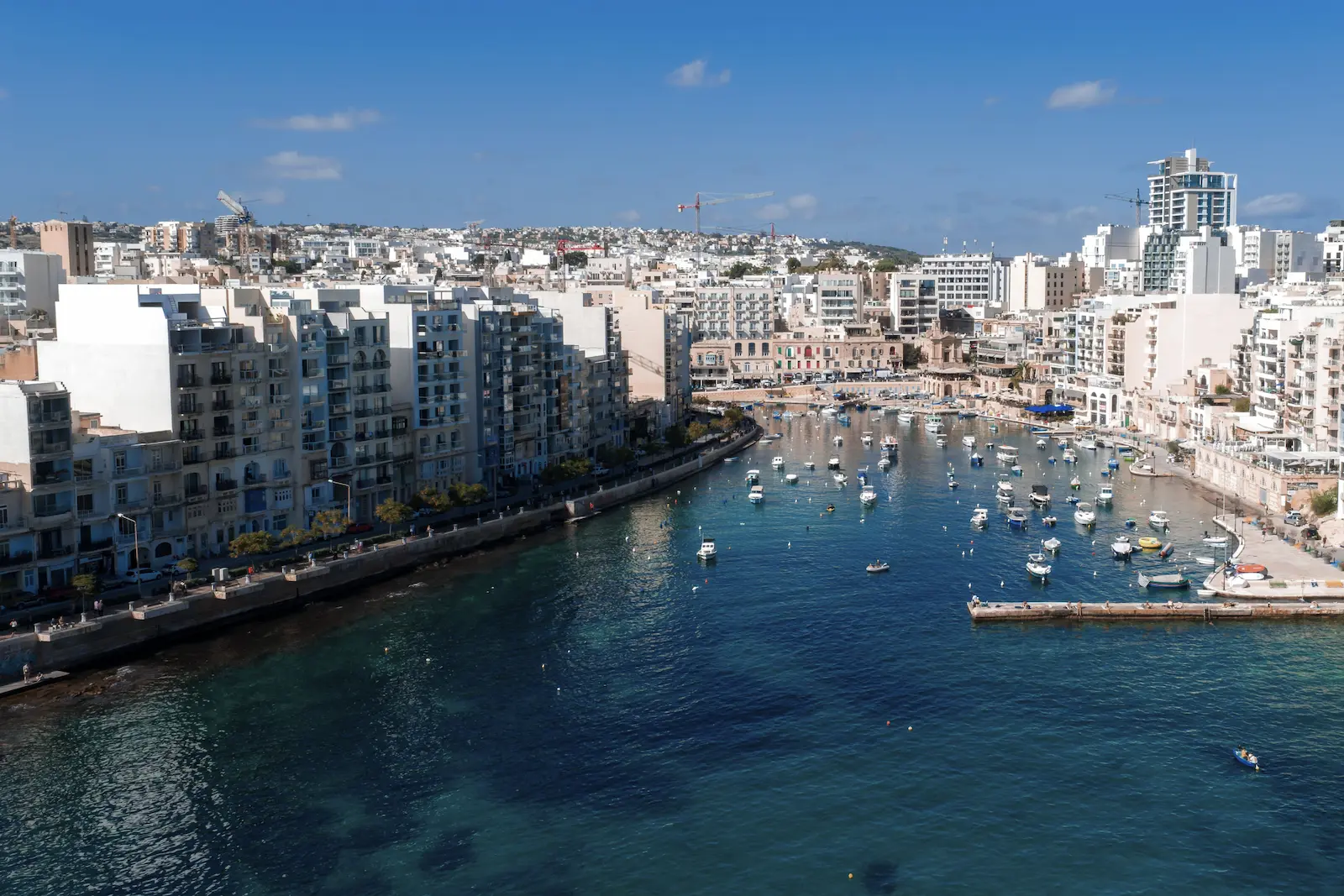 Panoramic view of Spinola Bay with boats and urban buildings in St. Julian’s, Malta